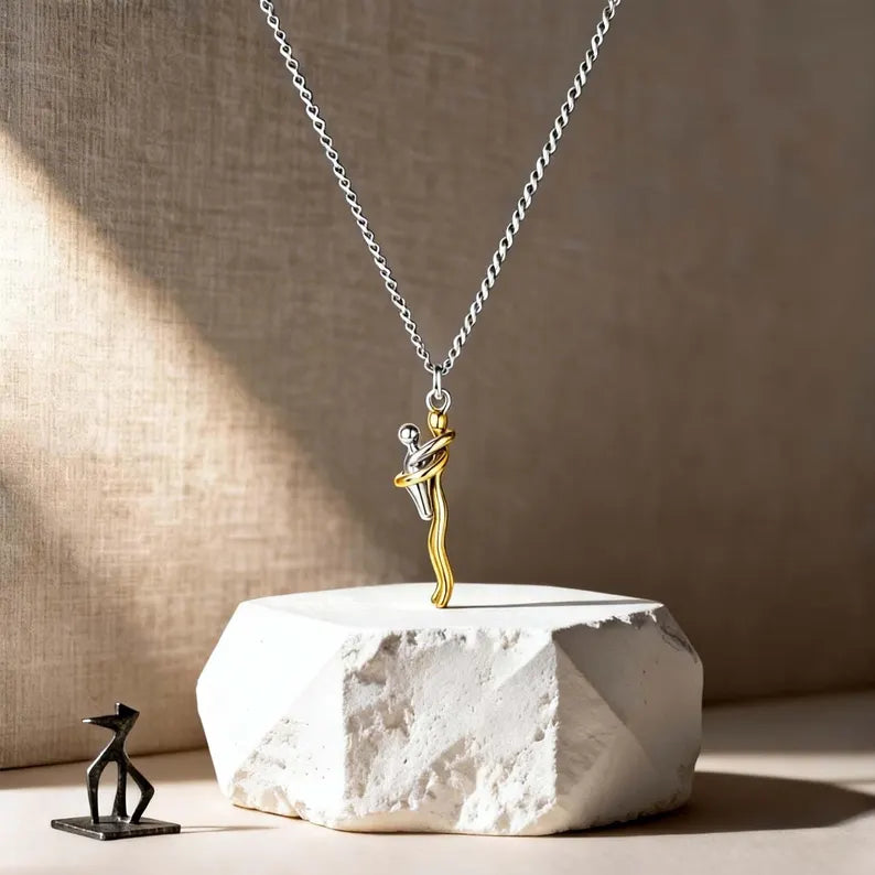 Necklace with a dancing figure pendant on a white stone surface with a neutral background